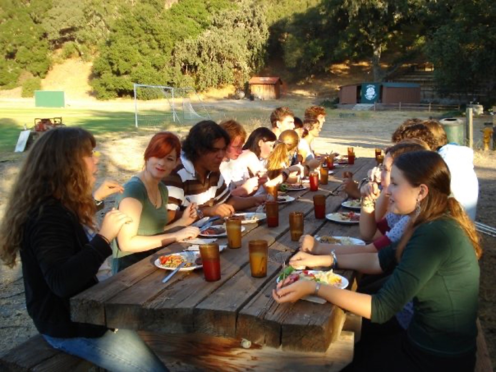 Midland School students sharing dinner at a long outdoor picnic table on campus