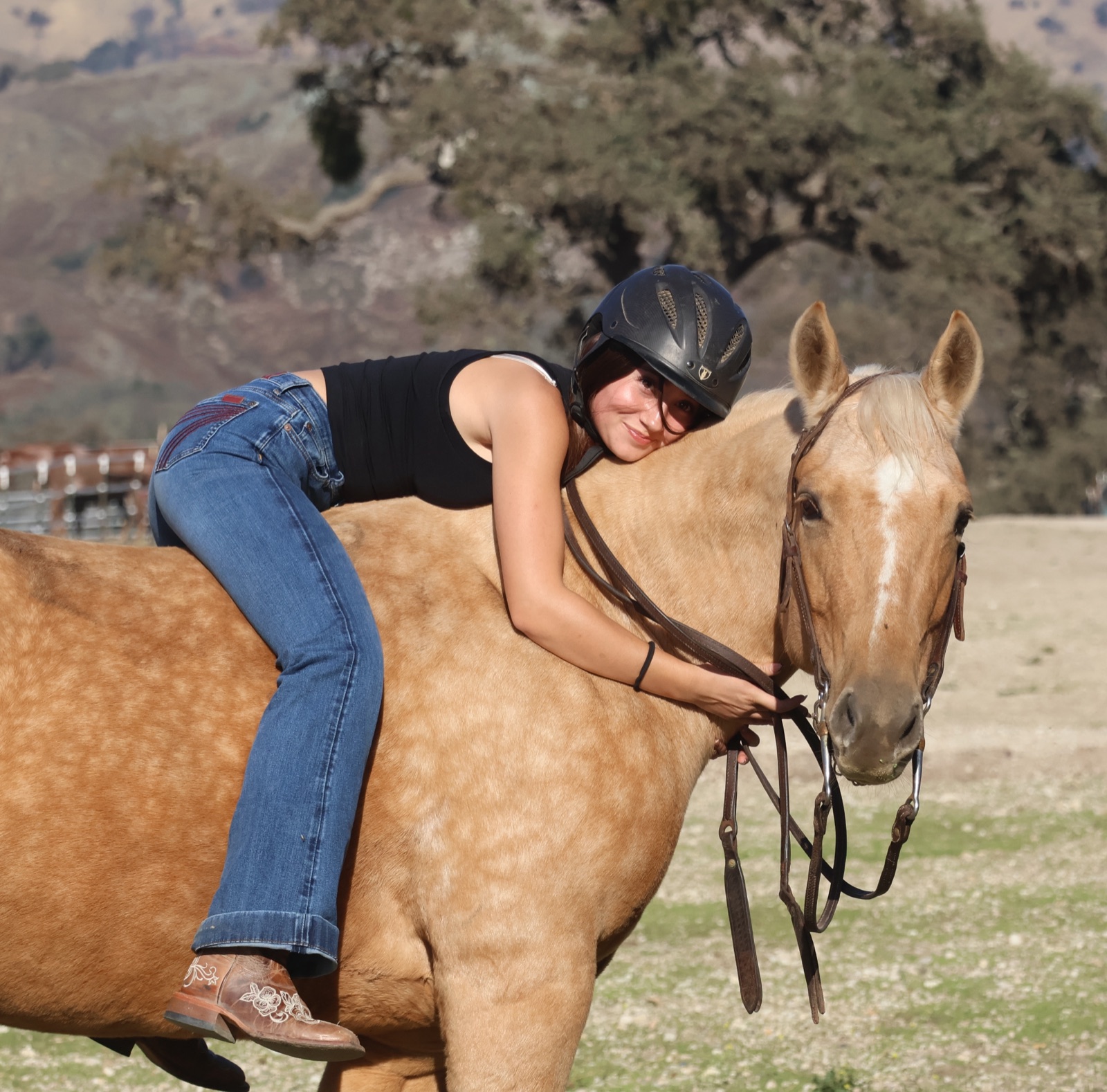 Bri ’29 lying forward on Peaches’ neck and smiling at the Midland barn