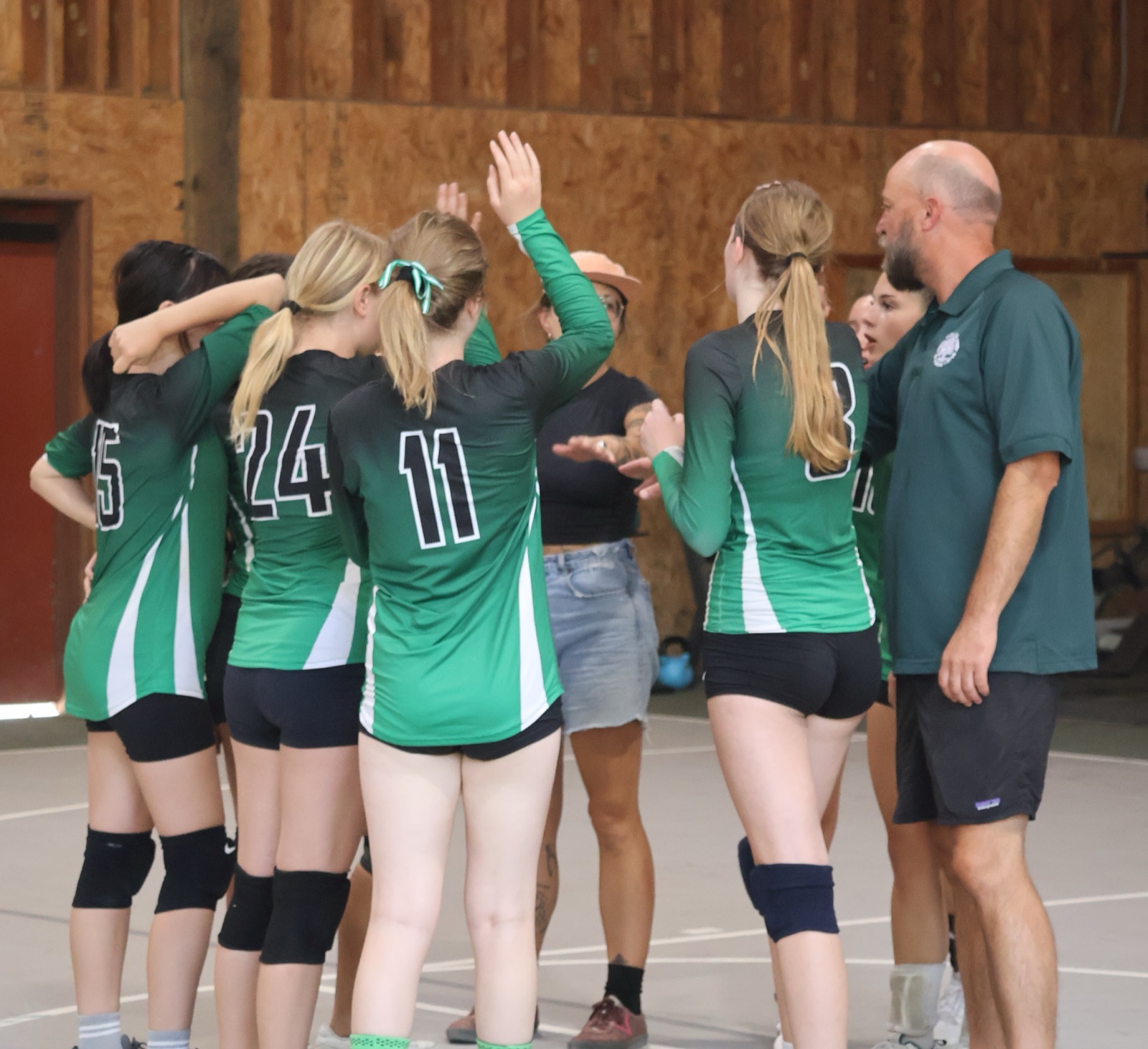 Midland volleyball players and coaches in a team huddle